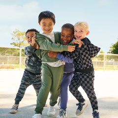 Four boys playing wearing various Play by Little Sleepies styles in Vintage Camo, Vintage Navy, Moss, and Monochrome Checks