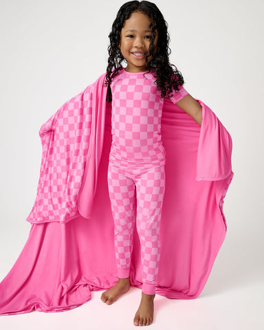 Girl wearing Sweet Raspberry Pajamas wrapped in a matching pink checkered blanket