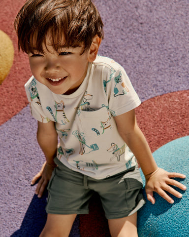 Child sitting on a playscape wearing the Whiskers & Wags Relaxed Pocket Tee
