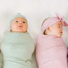 two children swaddled in a heather sage and heather mauve swaddle set