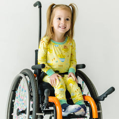 Child in a wheelchair wearing Little Chicks printed two piece pajamas