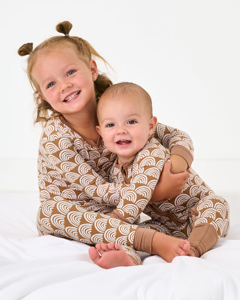 Two children wearing matching Rust Rainbows pajamas