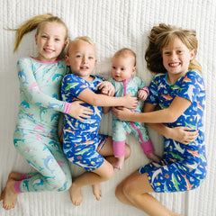 Four children laying on a blanket wearing Rad Reef and Dolphin Dance pajamas