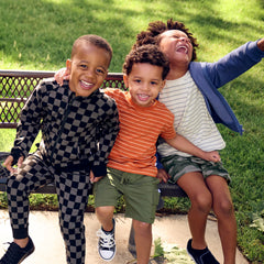 Three boys wearing various Play by Little Sleepies outfits and zip hoodies in Monochrome Checks and Vintage Navy styles