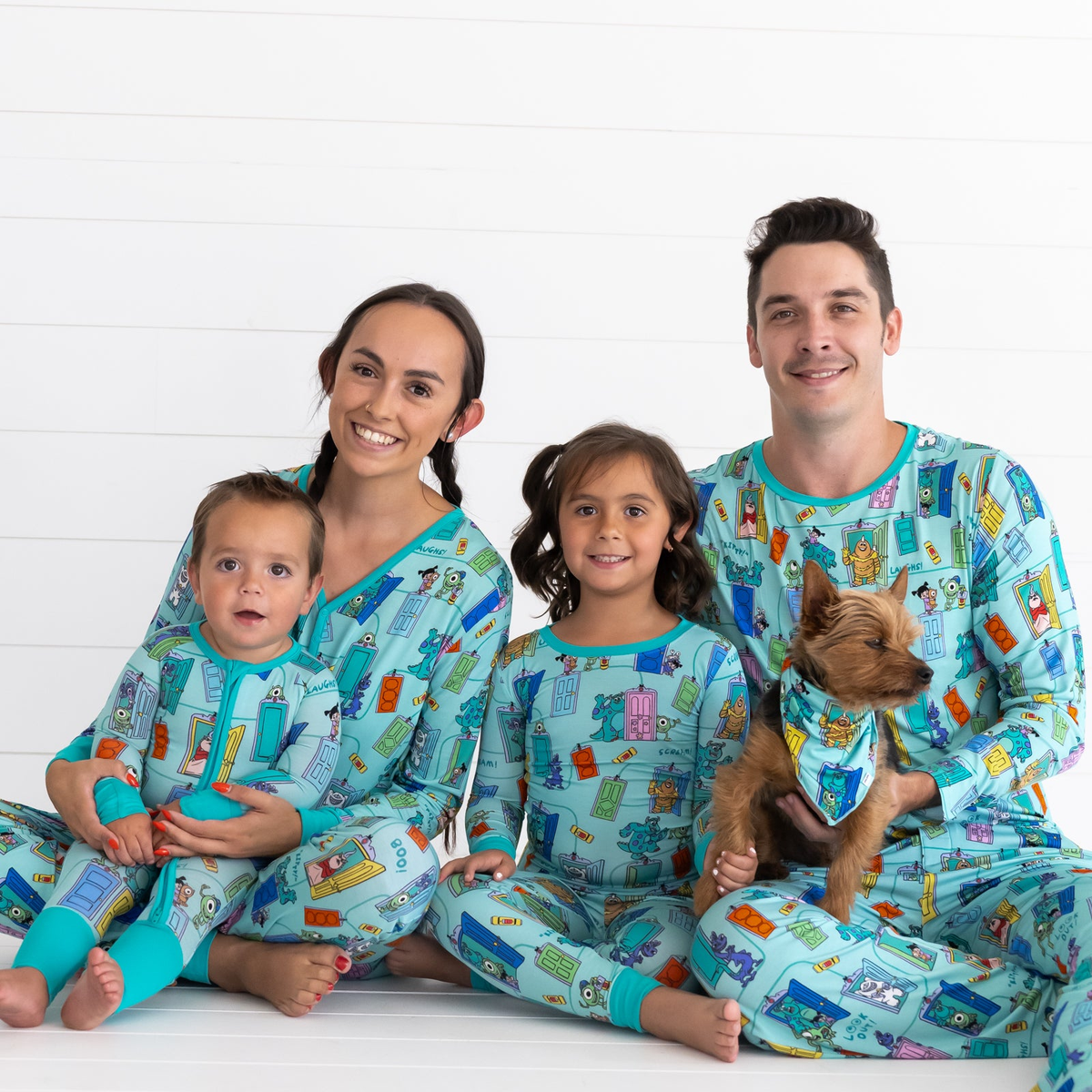 Family of four and a dog wearing matching Disney Monsters, Inc. Scream Team pajamas