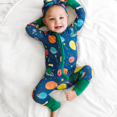 child laying on a bed wearing a Sleepy Galaxy printed zippy and luxe bow headband