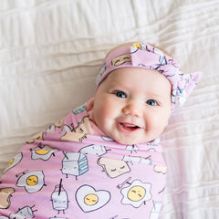 baby swaddled in a Pink Breakfast Buddies Swaddle and headband set