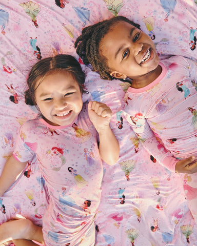 Two girls wearing Princess Garden Pajama Sets on a matching cloud blanket