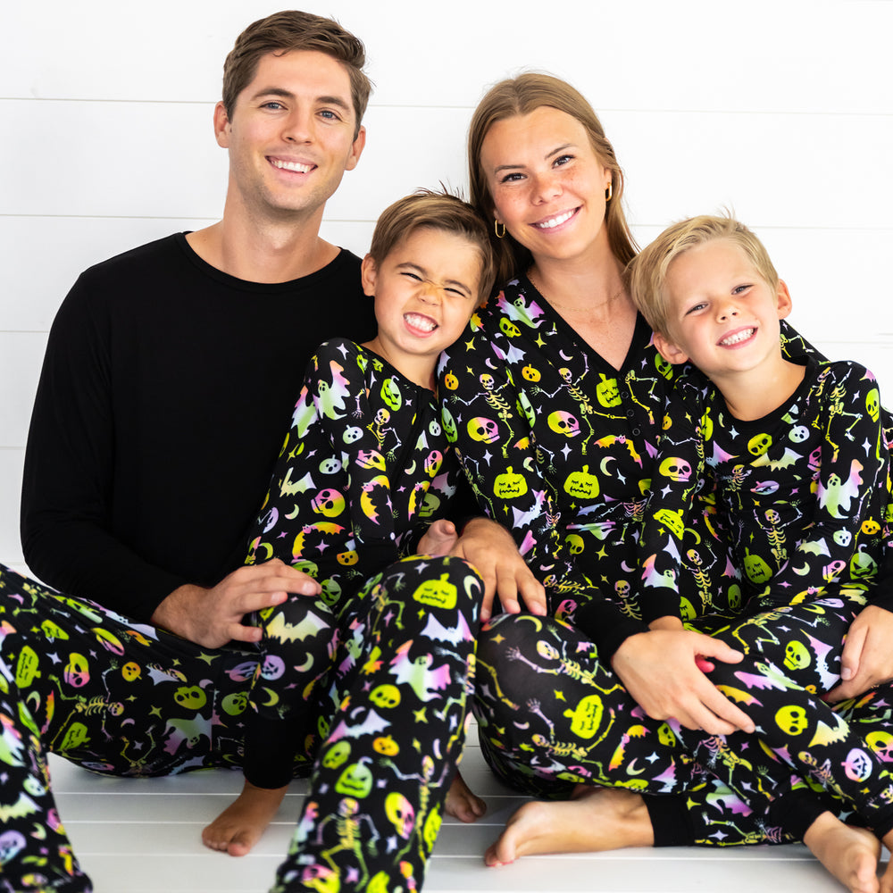 Family of four wearing matching men's, women's, and children's Cool Ghouls pjs. Children are wearing two piece styles