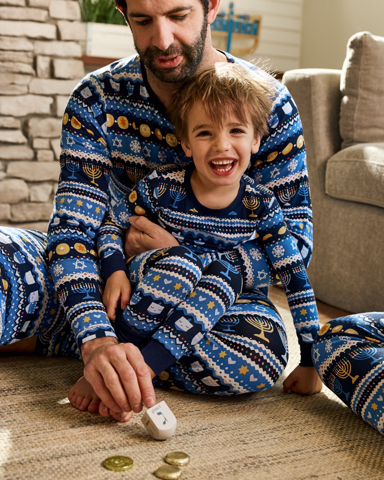 Father and son playing with a dreidel wearing matching Hanukkah Fair Isle 