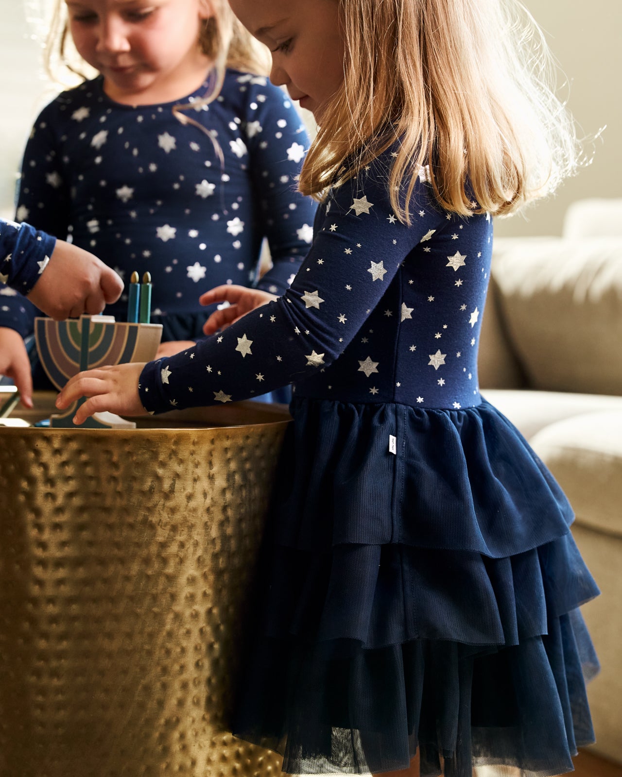 Girl wearing the Hanukkah Stars Tiered Tutu Dress with Bloomer playing with a holiday toy 