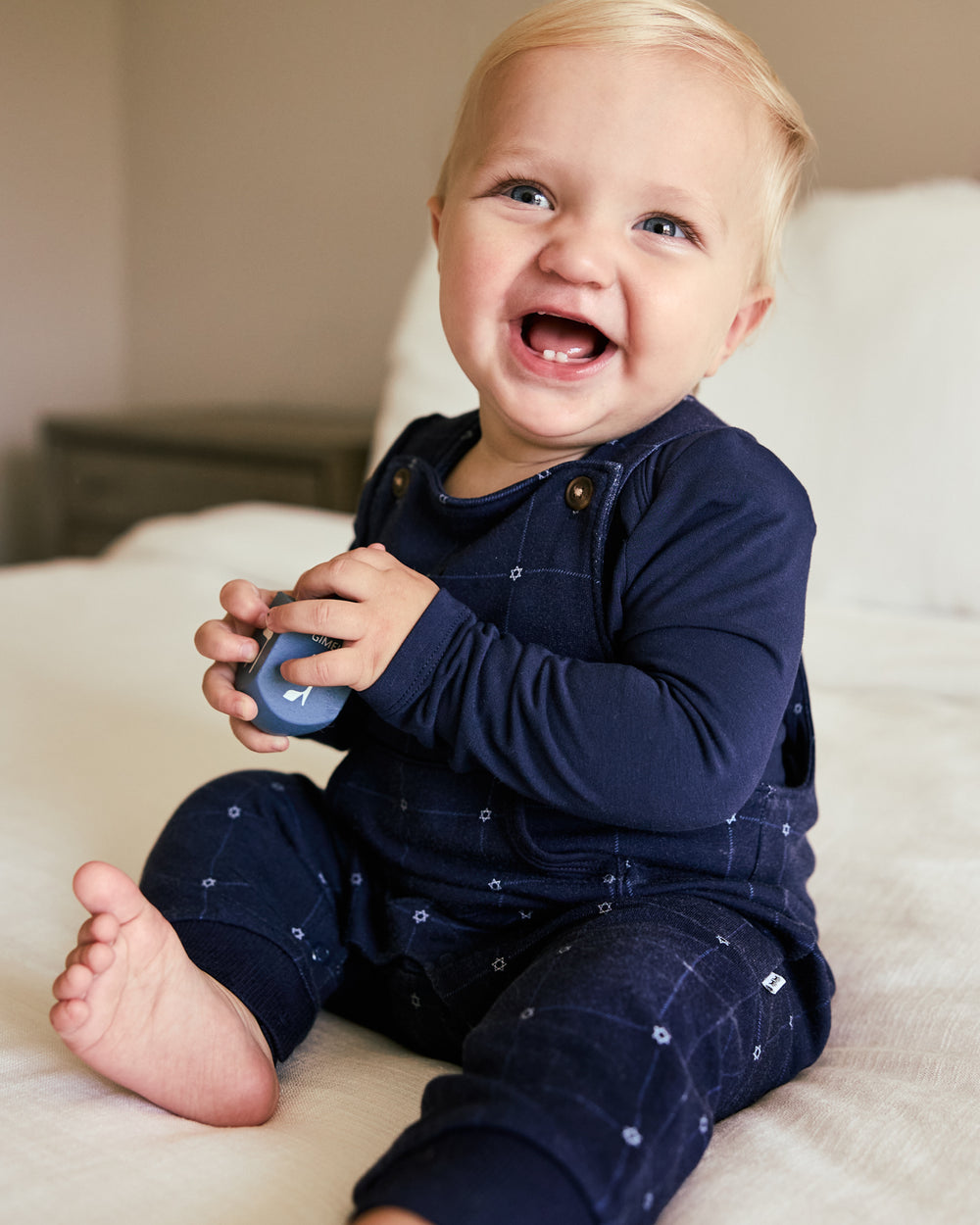 Child wearing the Hanukkah Stars Overall layered over a blue bodysuit