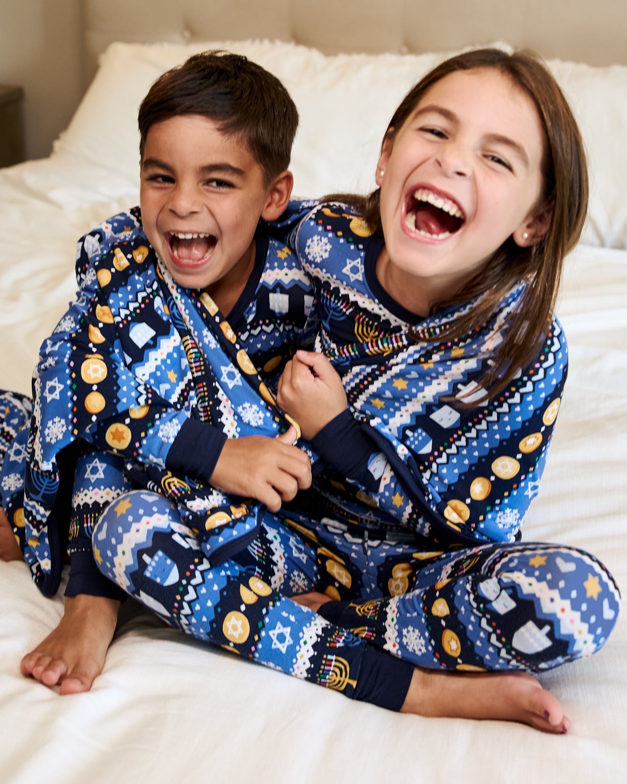 Two children wrapped in the Hanukkah Fair Isle Large Cloud Blanket®