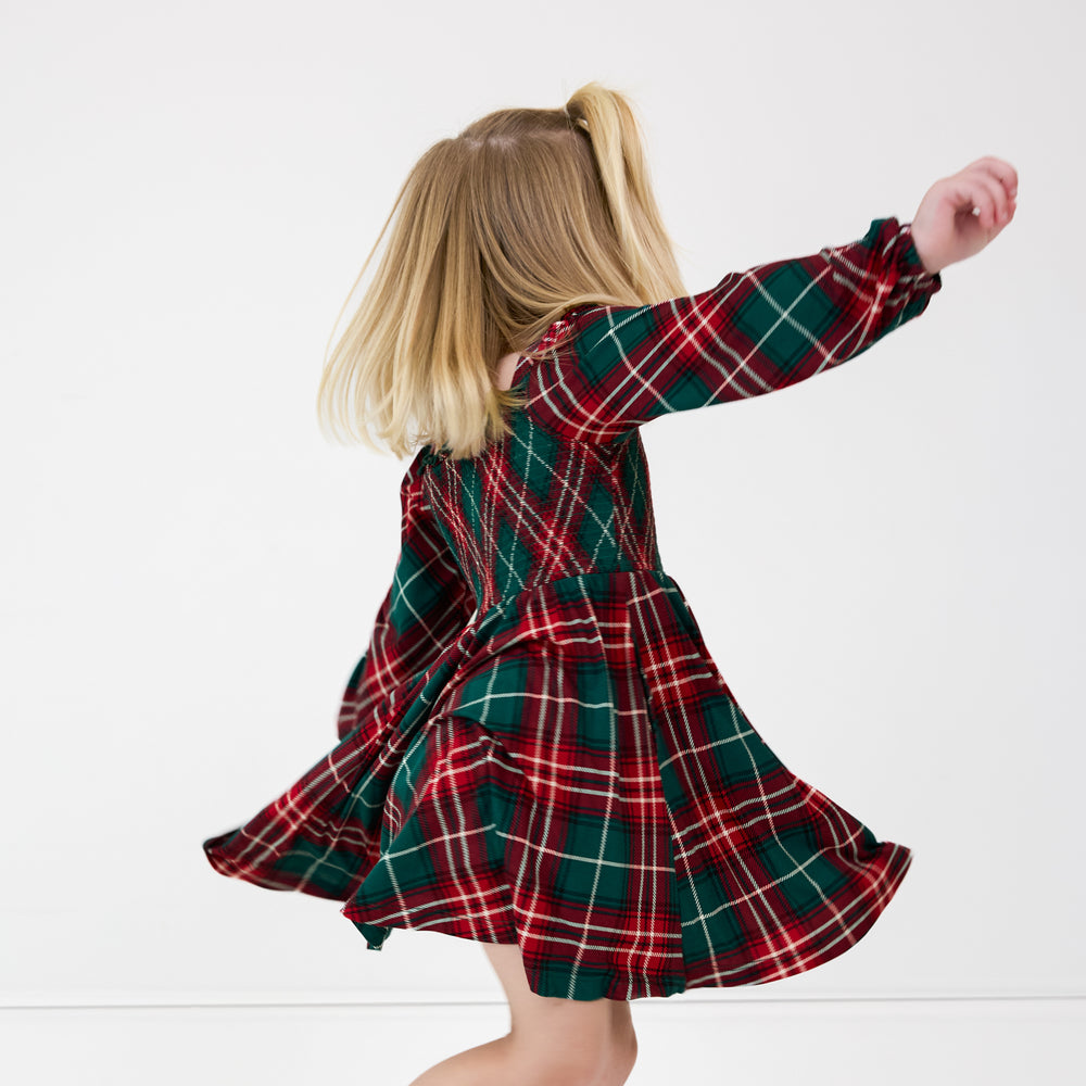 Image of a girl spinning around wearing a Fireside Plaid Smocked Dress with Bloomer