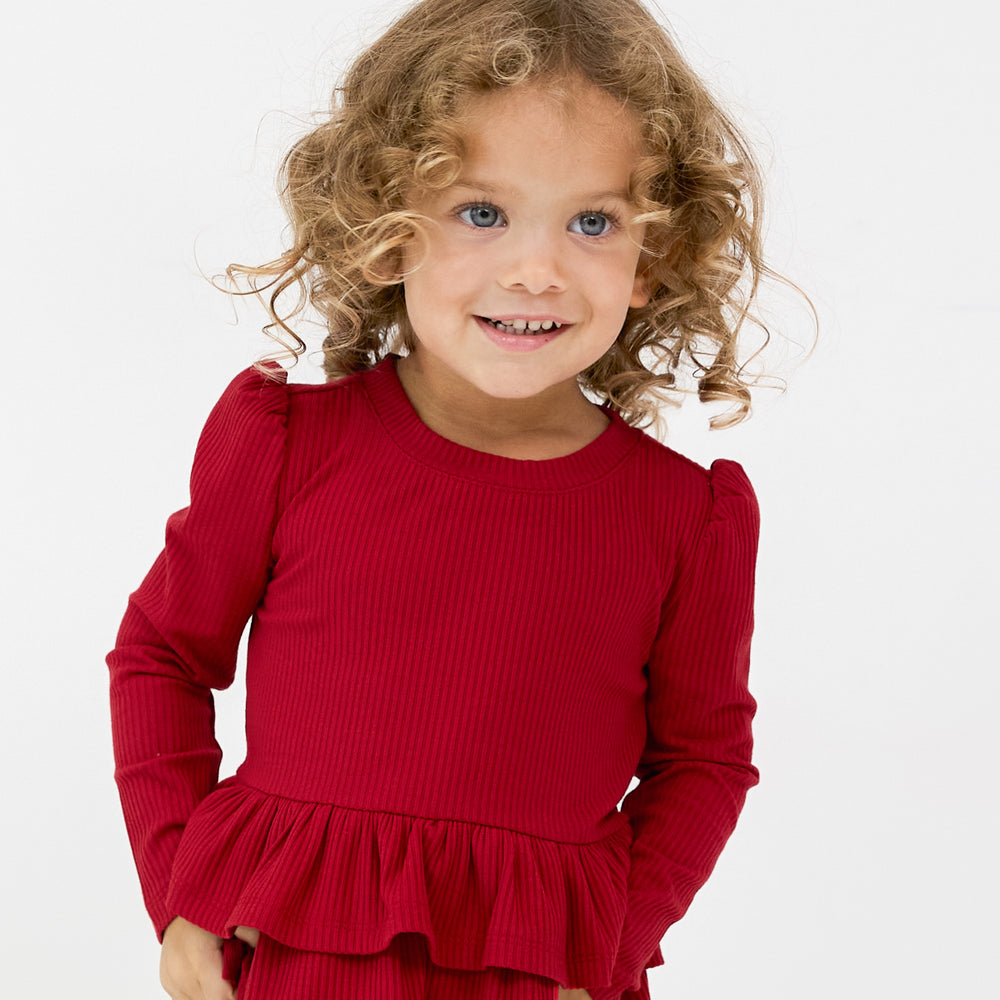 Close up image of a child wearing a Holiday Red Ribbed Tiered Peplum Top