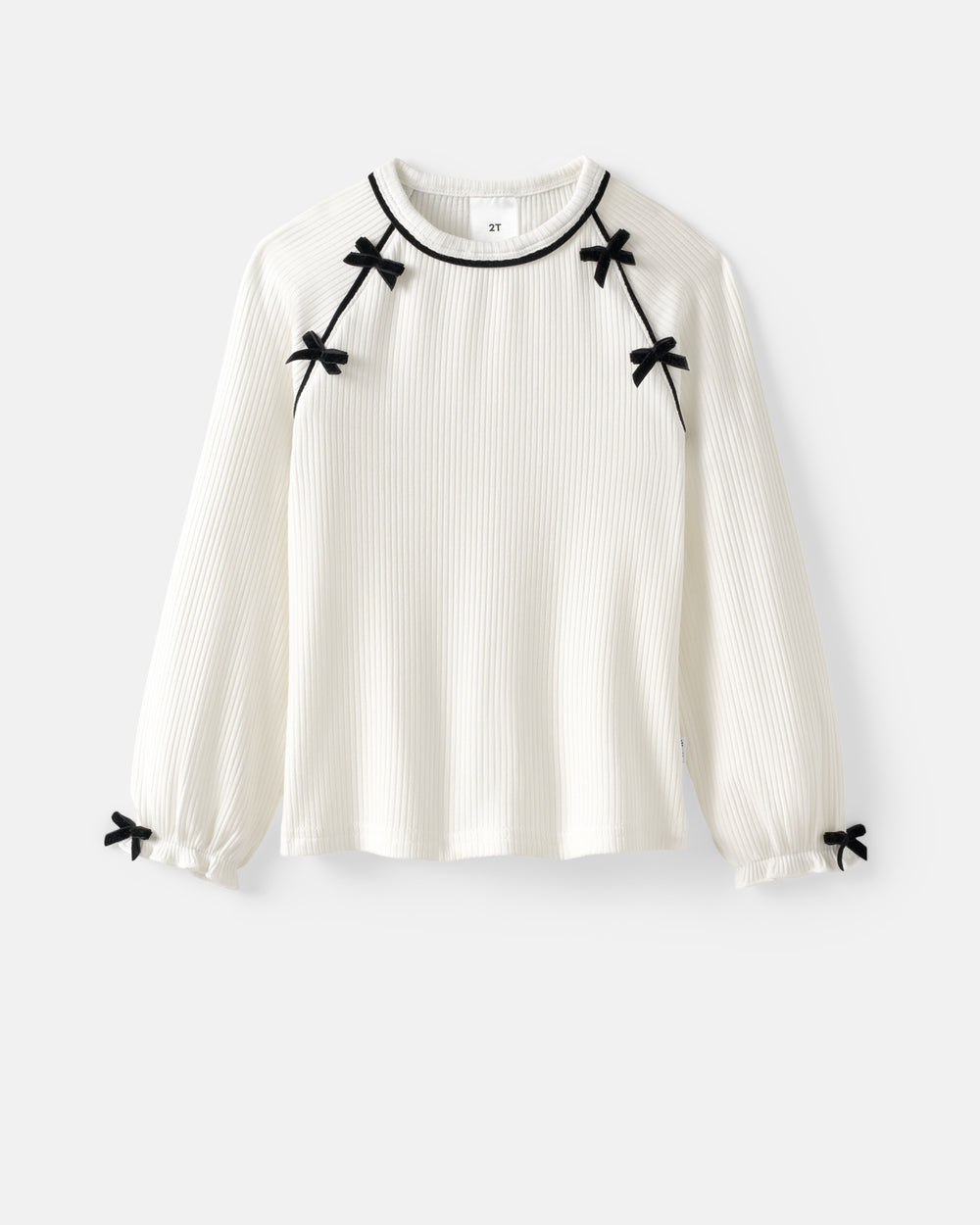 An off-white ribbed long-sleeve blouse with black trim around the crew neck and small black bow details at the shoulders, cuffs, and hem, shown against a light gray background.