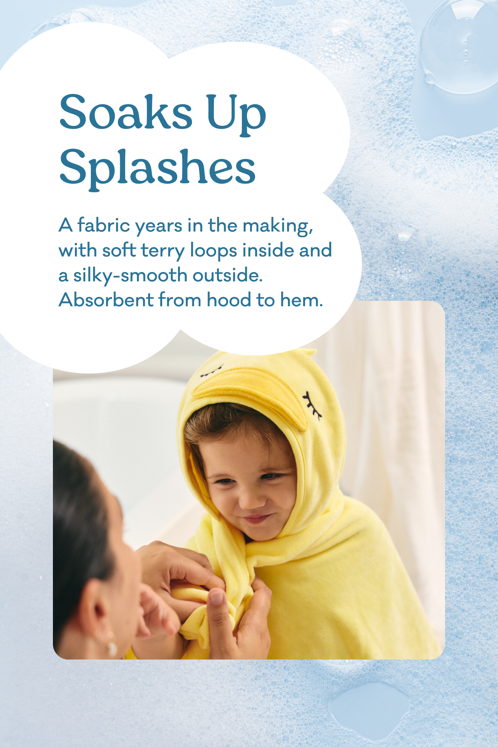 A child wearing a yellow hooded towel wrap with a face patch, being helped by an adult, set against a light blue bubbly background with text reading 'Soaks Up Splashes. A fabric years in the making, with soft terry loops inside and a silky-smooth outside. Absorbent from hood to hem.'