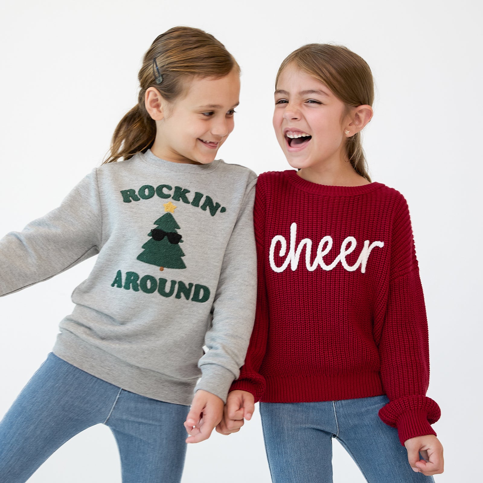 Two children holding hands wearing Holiday Play crewnecks