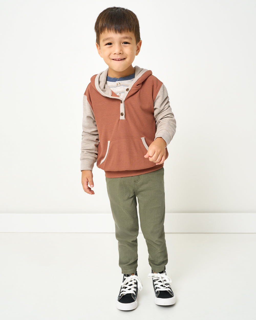 Boy wearing the Autumn Spice Waffle Henley Hoodie with green pants