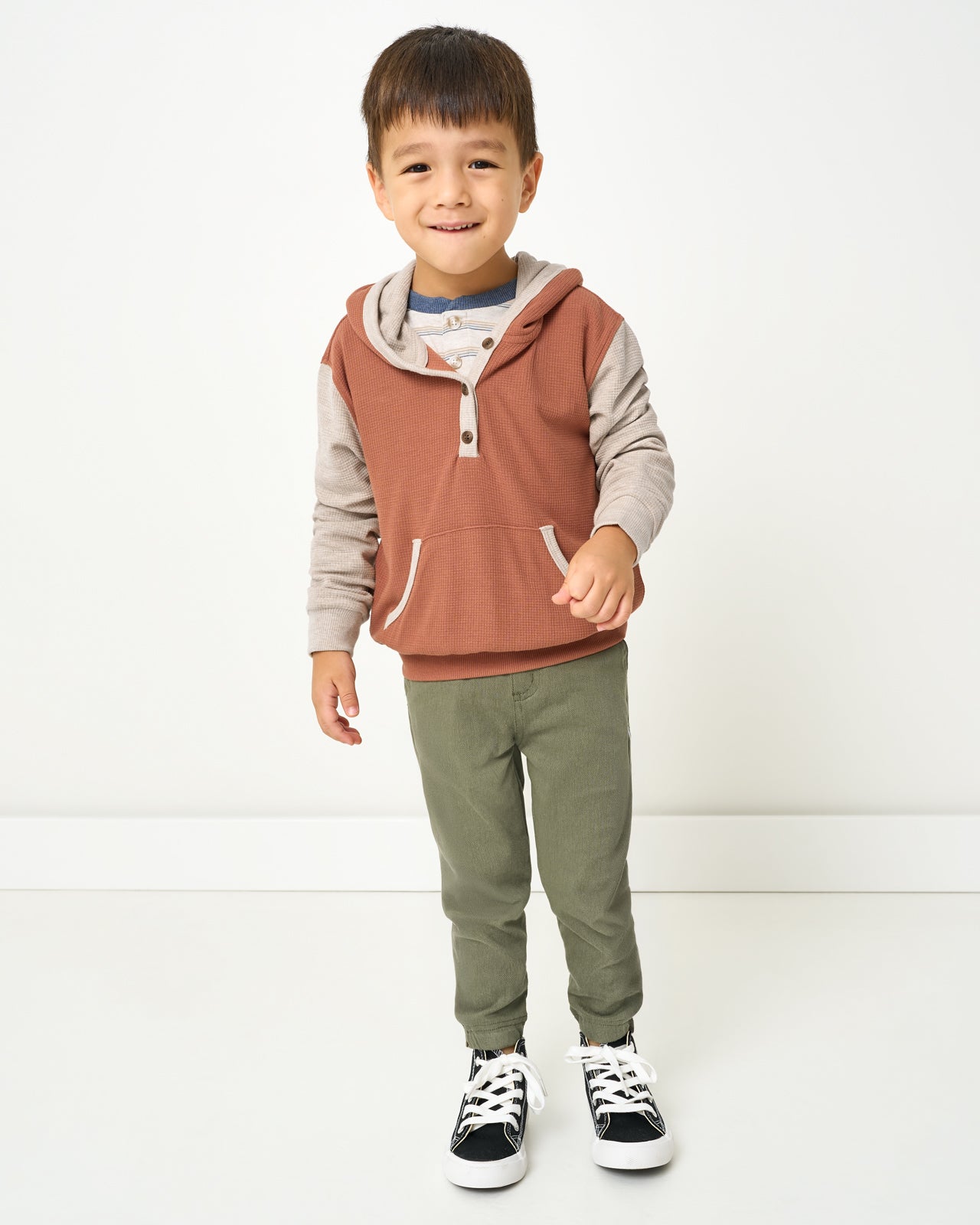 Boy wearing the Autumn Spice Waffle Henley Hoodie with green pants