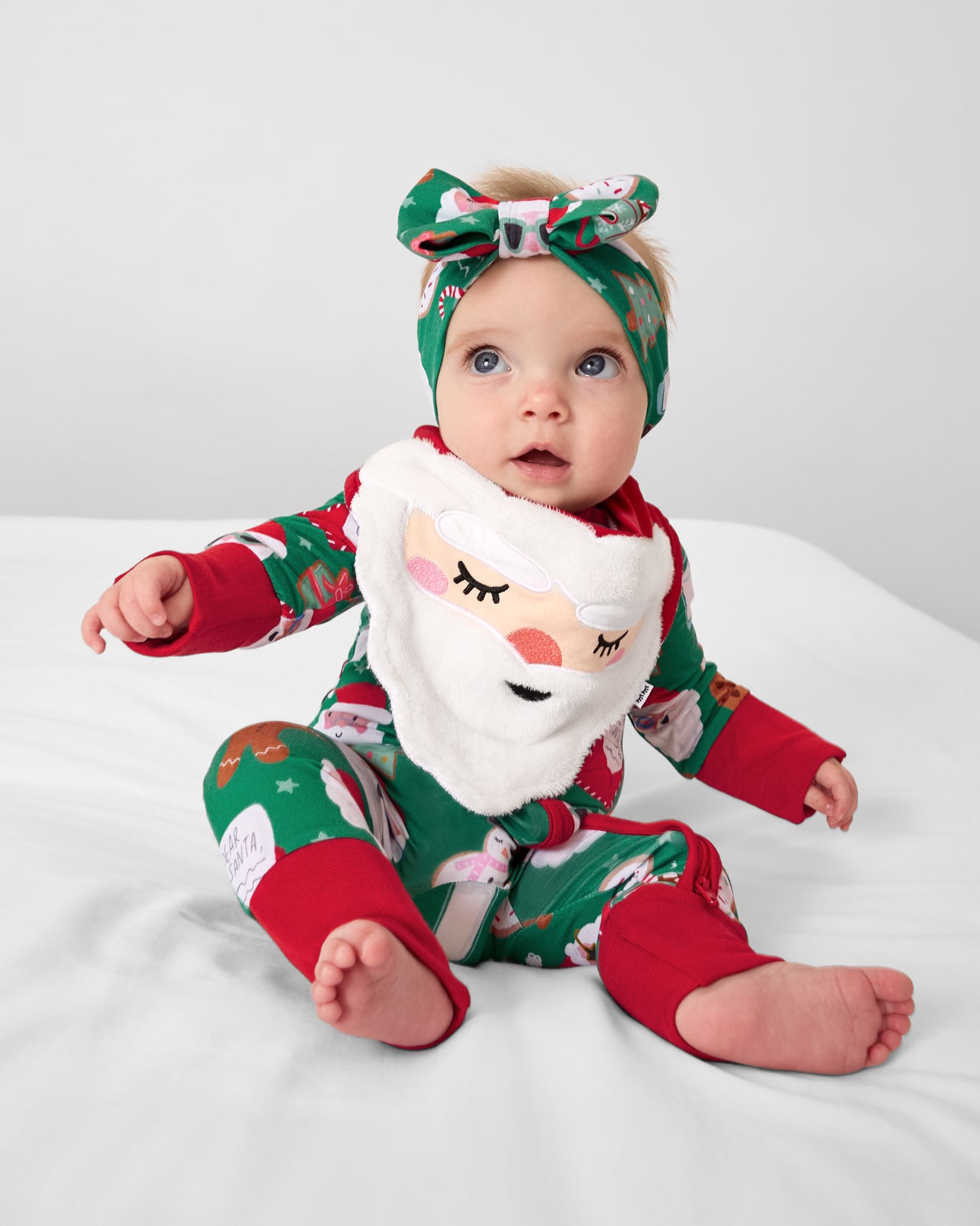 Baby wearing the Santa Bandana Bib with a holiday themed zipper pajama