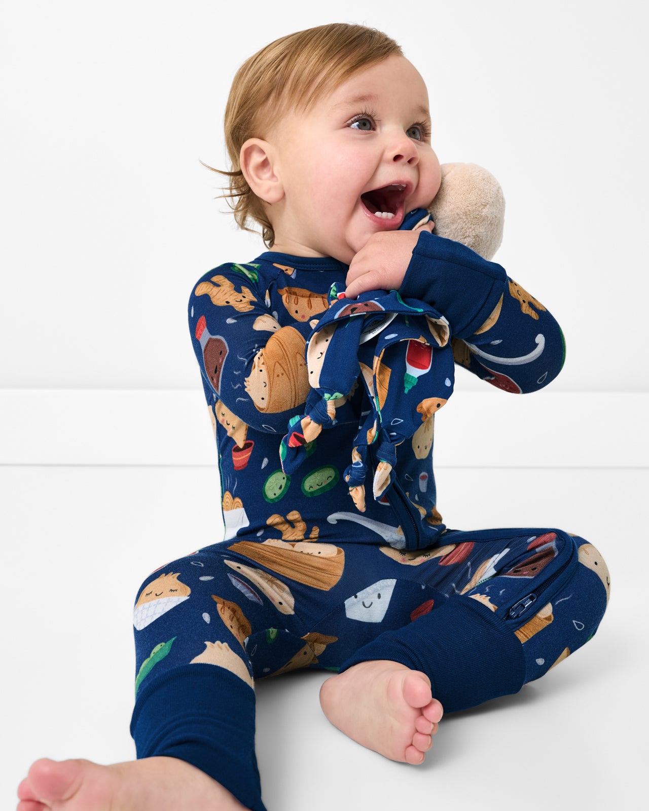 Sitting child wearing the Bao Buddies Zippy holding a plush toy
