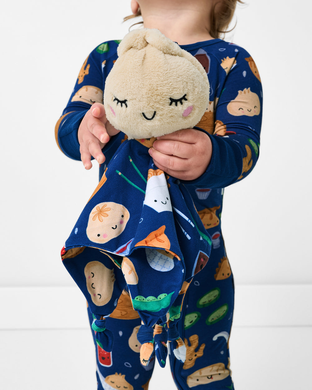 Child holding the Suki the Dumpling Sleepyhead Lovey