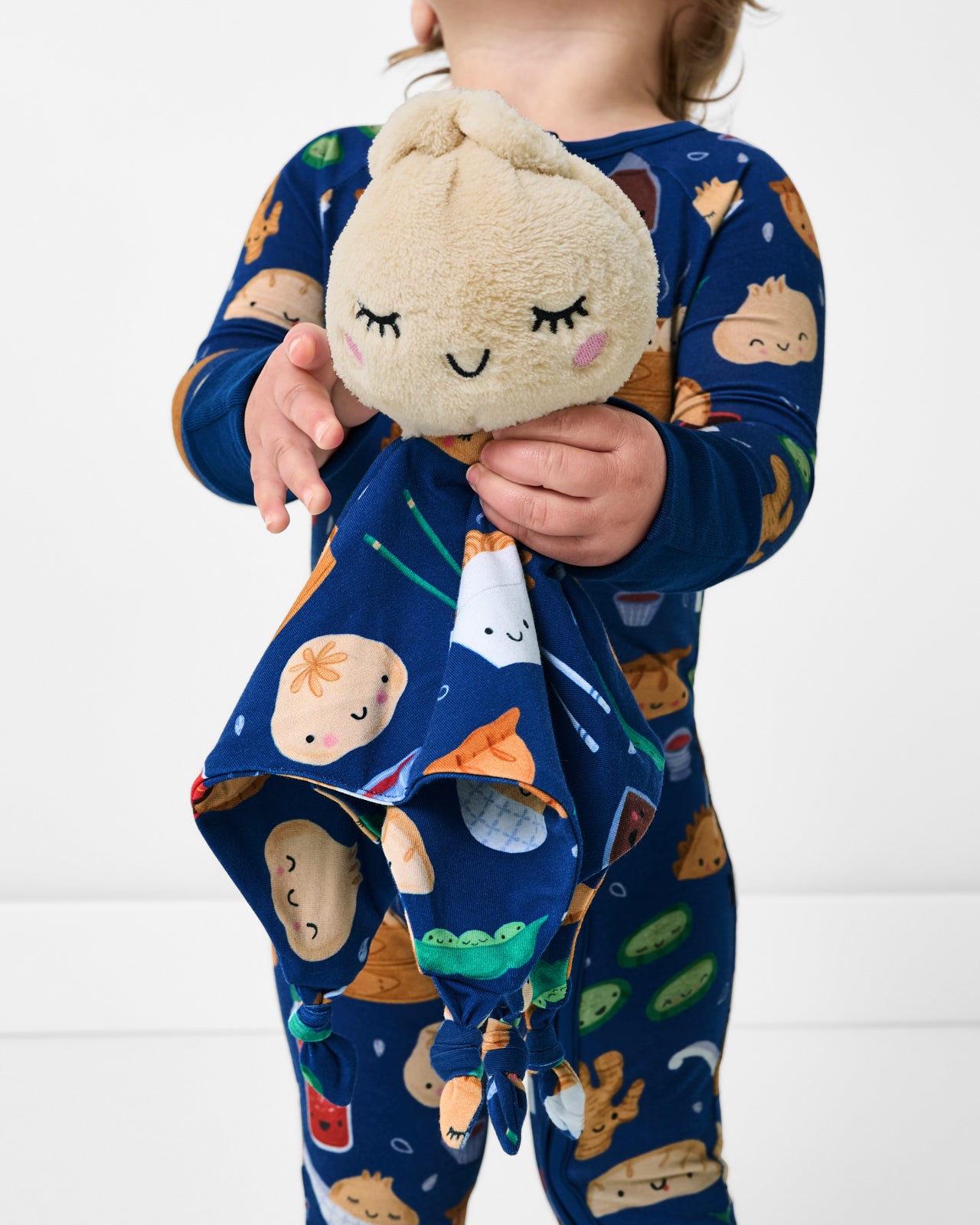 Child holding the Suki the Dumpling Sleepyhead Lovey