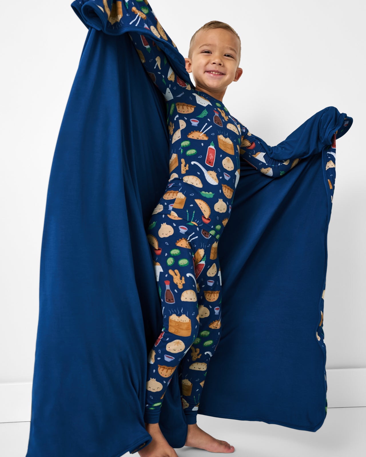 Boy holding up the Bao Buddies Large Cloud Blanket® showing the solid blue side