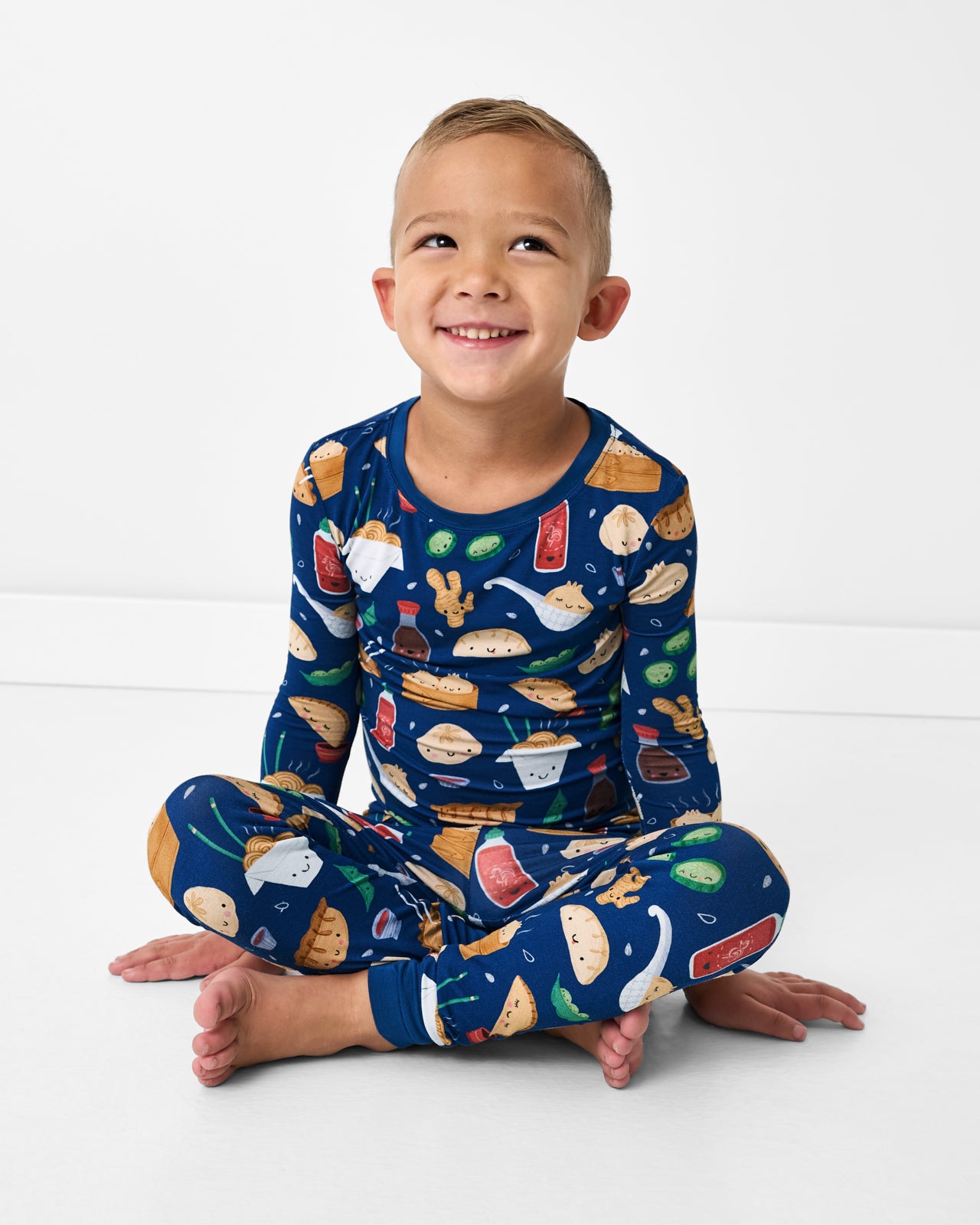 Sitting boy wearing the Bao Buddies Two-Piece Pajama Set