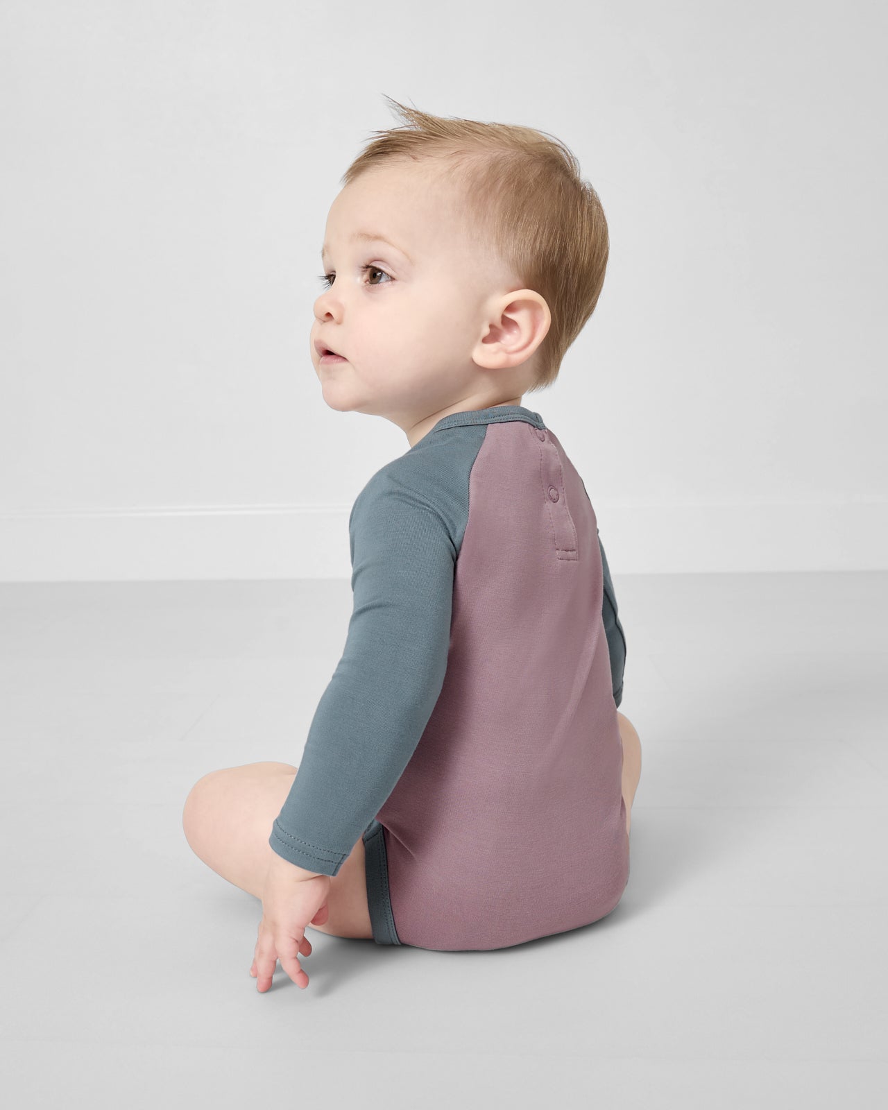 Back view of sitting baby wearing the Bolt Raglan Bodysuit