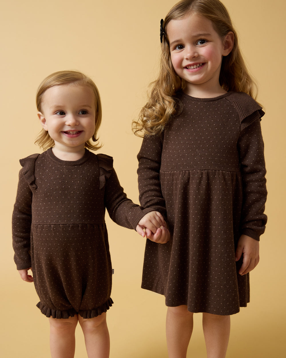 Two girls wearing Mocha Sweater styles on a yellow background