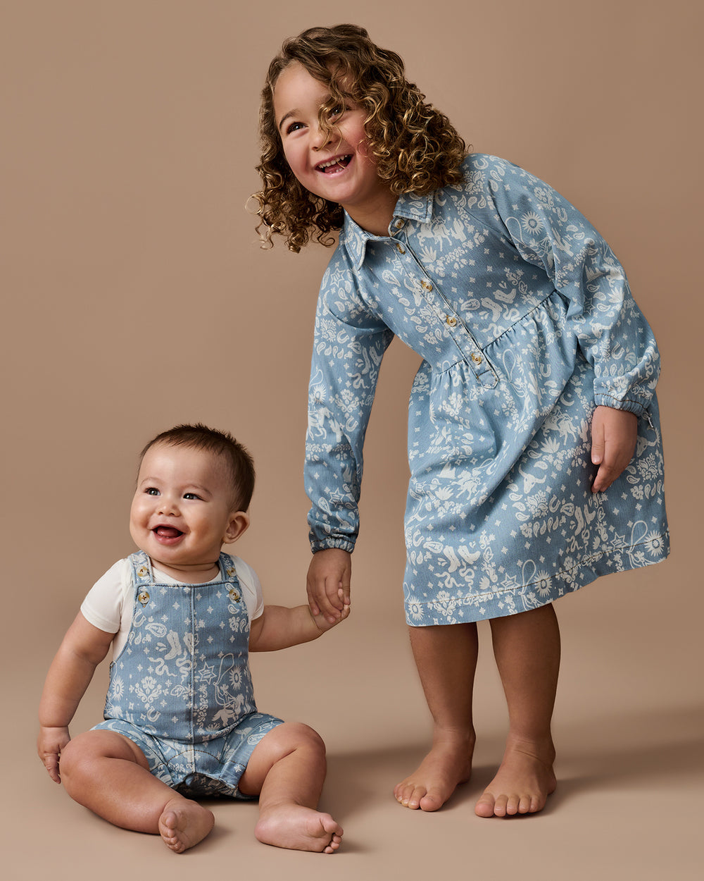 Two children wearing matching Bandana Blues Denim styles on a brown background