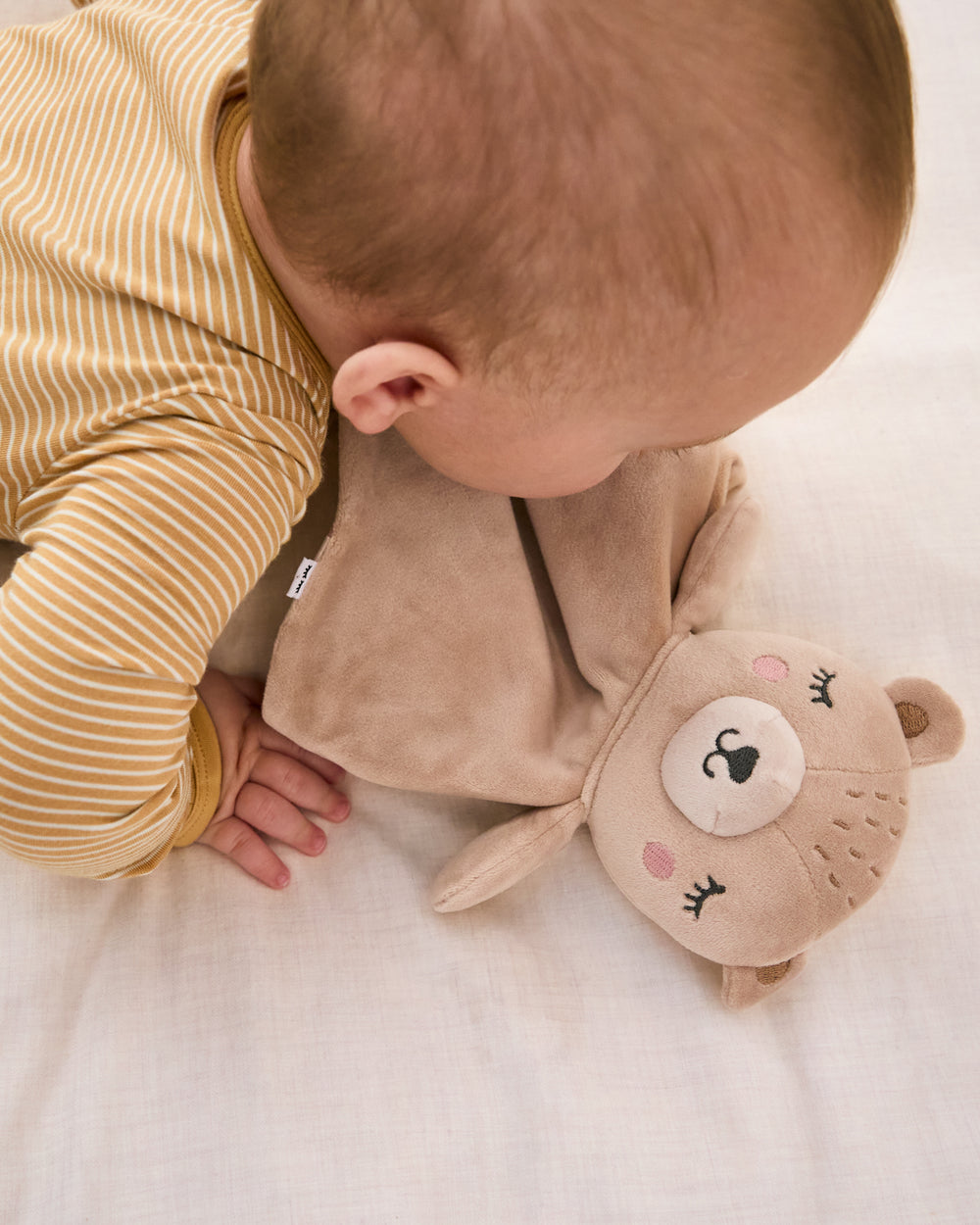Baby laying with the Bear Sleepyhead Lovey