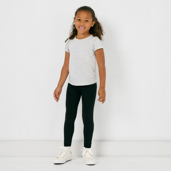 Standing child wearing the Black Legging with a gray puff sleeve tee