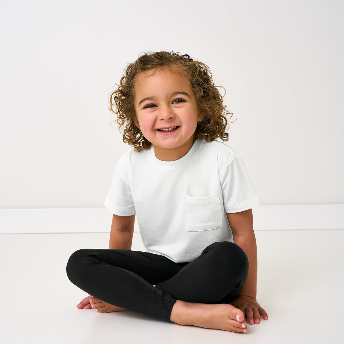 Sitting child wearing the Black Legging and white pocket tee