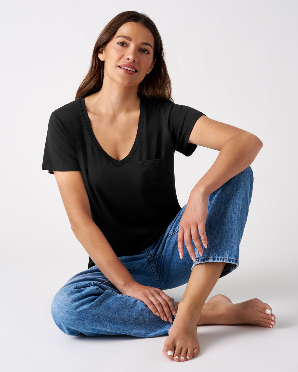Sitting woman wearing the Black Women's Perfect Pocket Tee with midwash jeans 