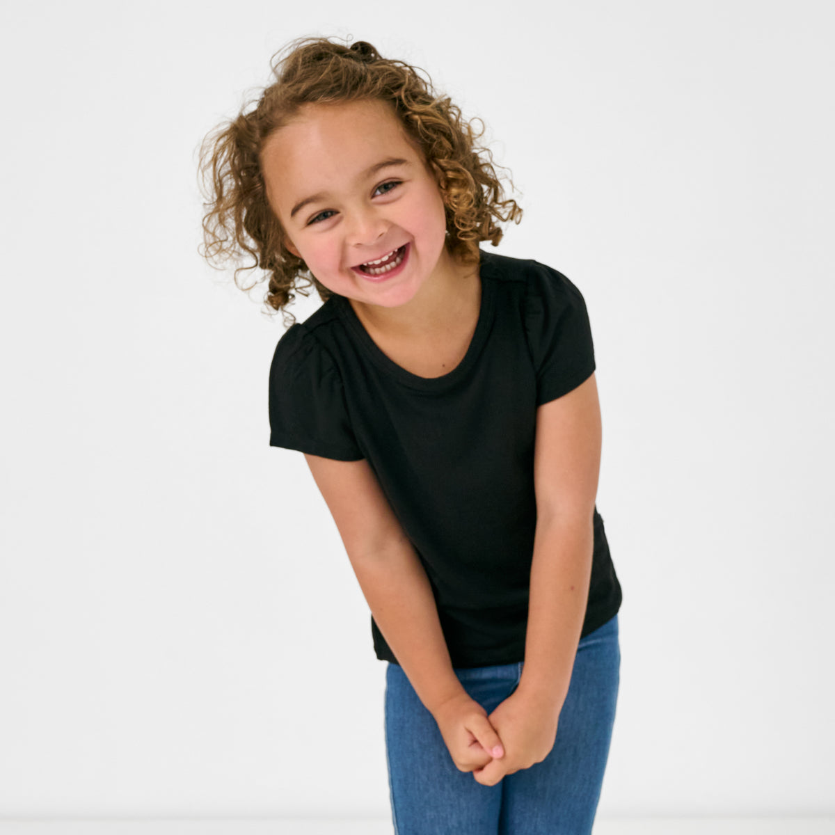 Posing child wearing the Black Puff Sleeve Tee with blue jeans