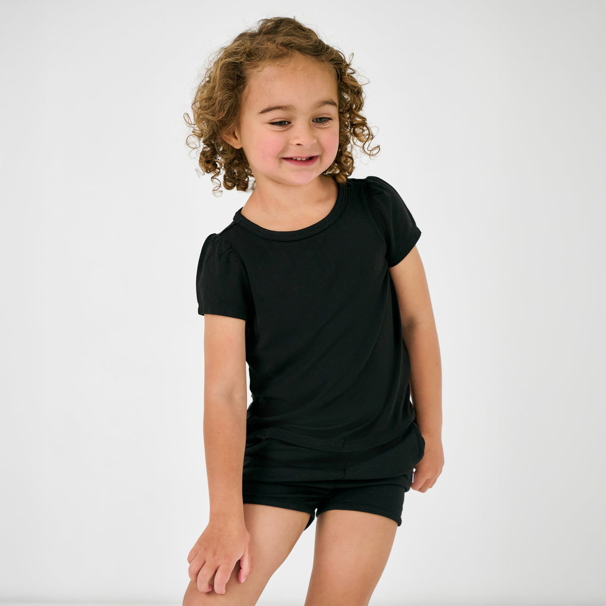 Standing child wearing the Black Puff Sleeve Tee with black shorts