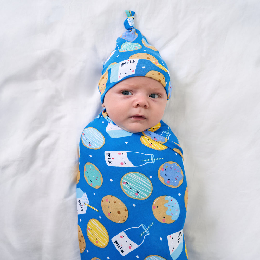 Close up of baby wearing the Blue Cookies & Milk Swaddle & Hat Set