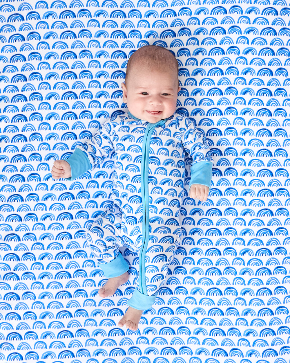 Alternate baby laying on the Blue Rainbows Fitted Crib Sheet