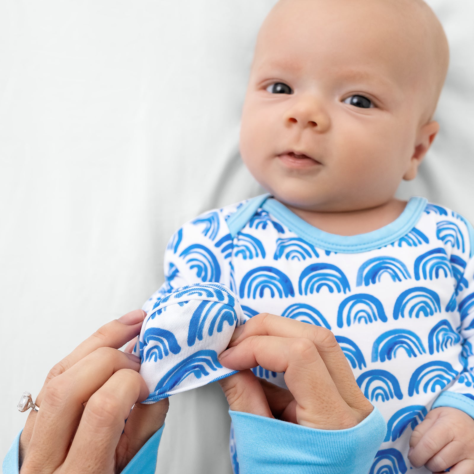 Adult demonstrating he hand fold over feature on the Blue Rainbows Infant Gown