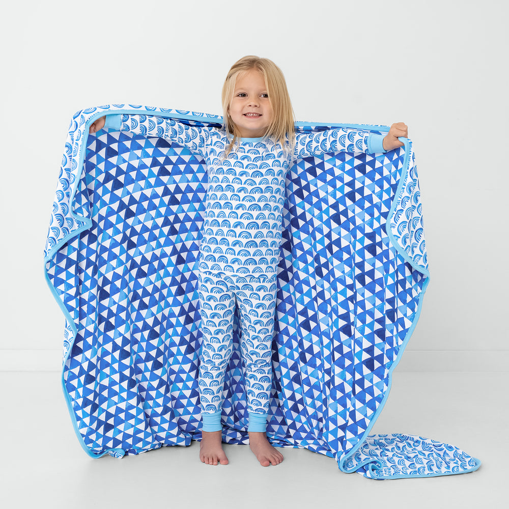 Standing child holding up the Blue Rainbows Large Cloud Blanket®