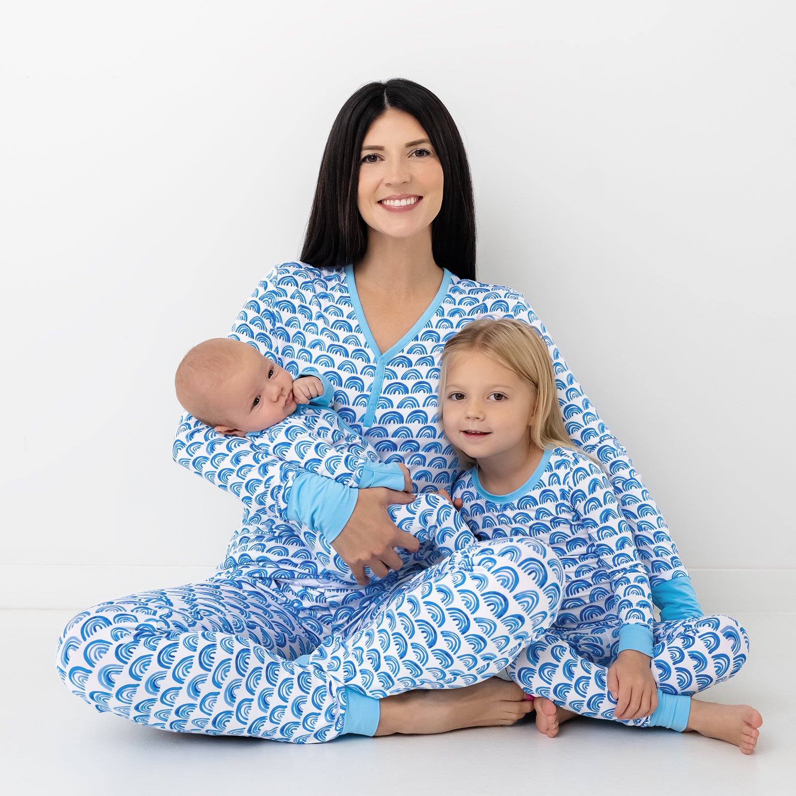 Mother and two children wearing matching Blue Rainbows Pajamas
