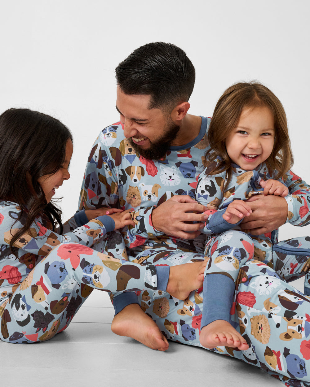 Man and two children wearing matching Gray Puppy Parade dog print pajamas