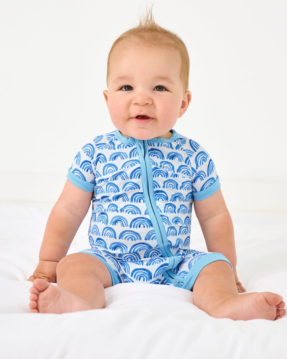Sitting baby wearing the Blue Rainbows Shorty Zippy