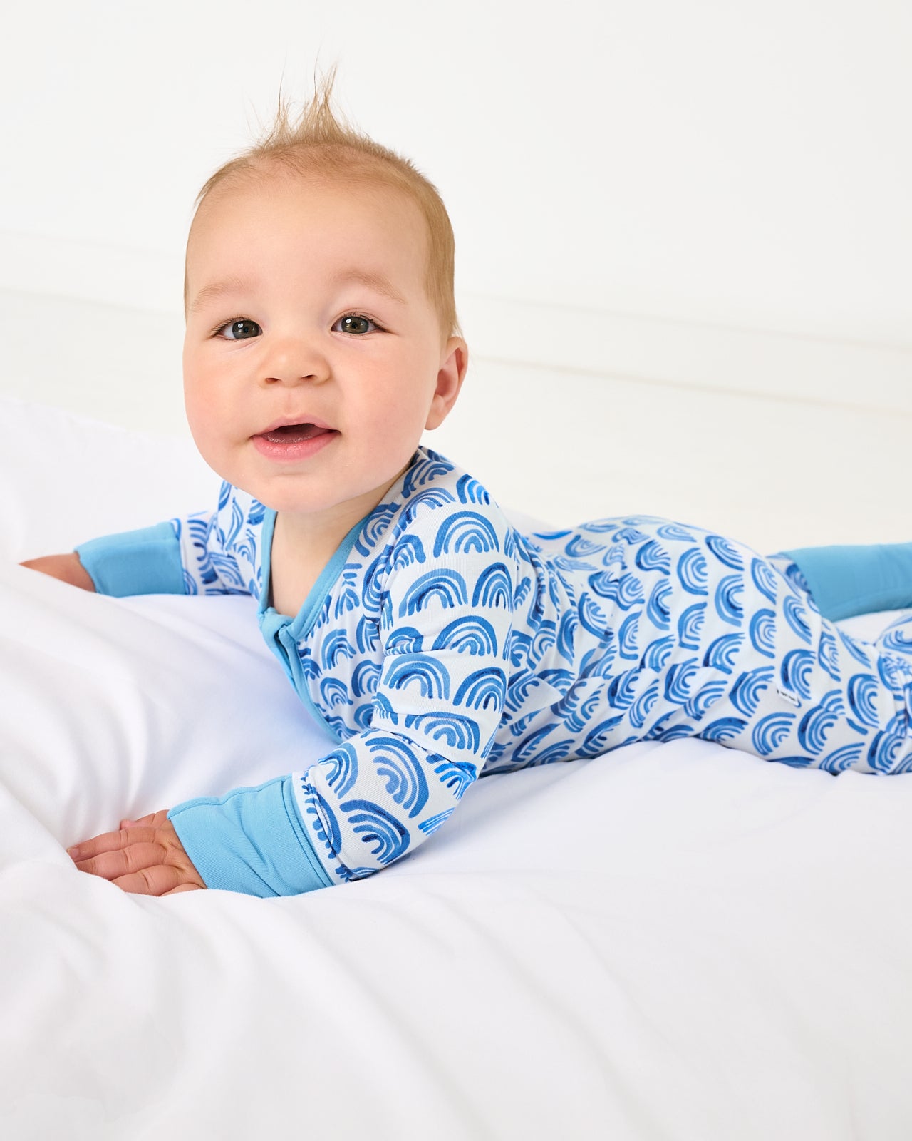 Laying baby wearing the Blue Rainbows Zippy