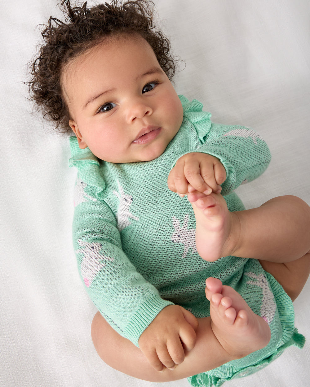 Close up of baby wearing the Blush Bunnies Sweater Bubble Romper on a white background