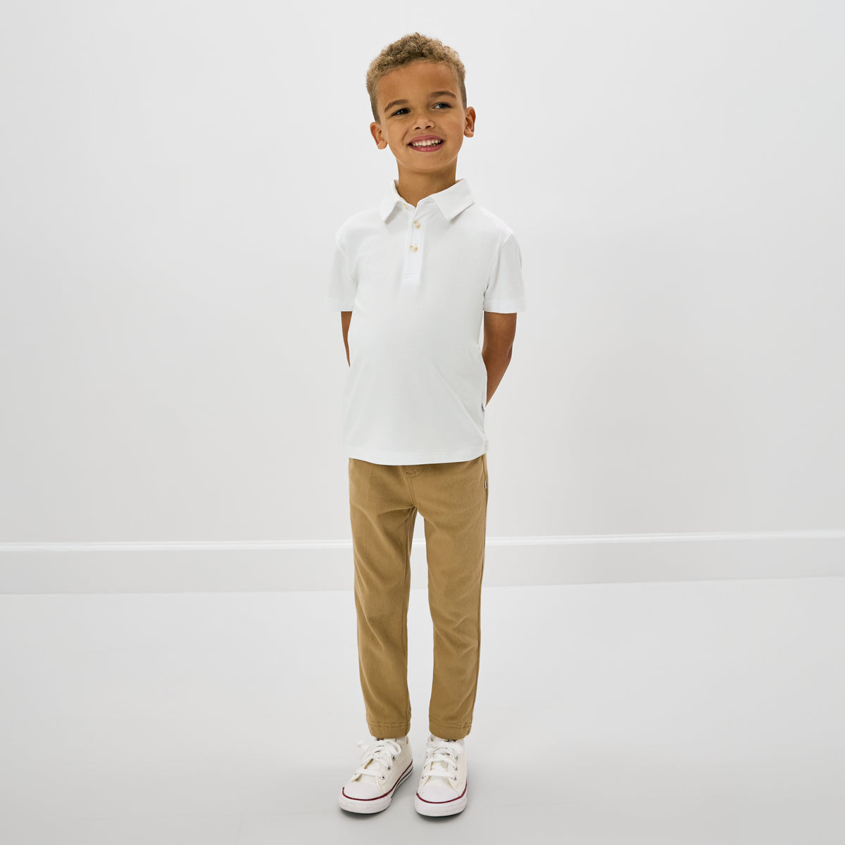 Standing child wearing the Bright White Polo Shirt with khaki pants