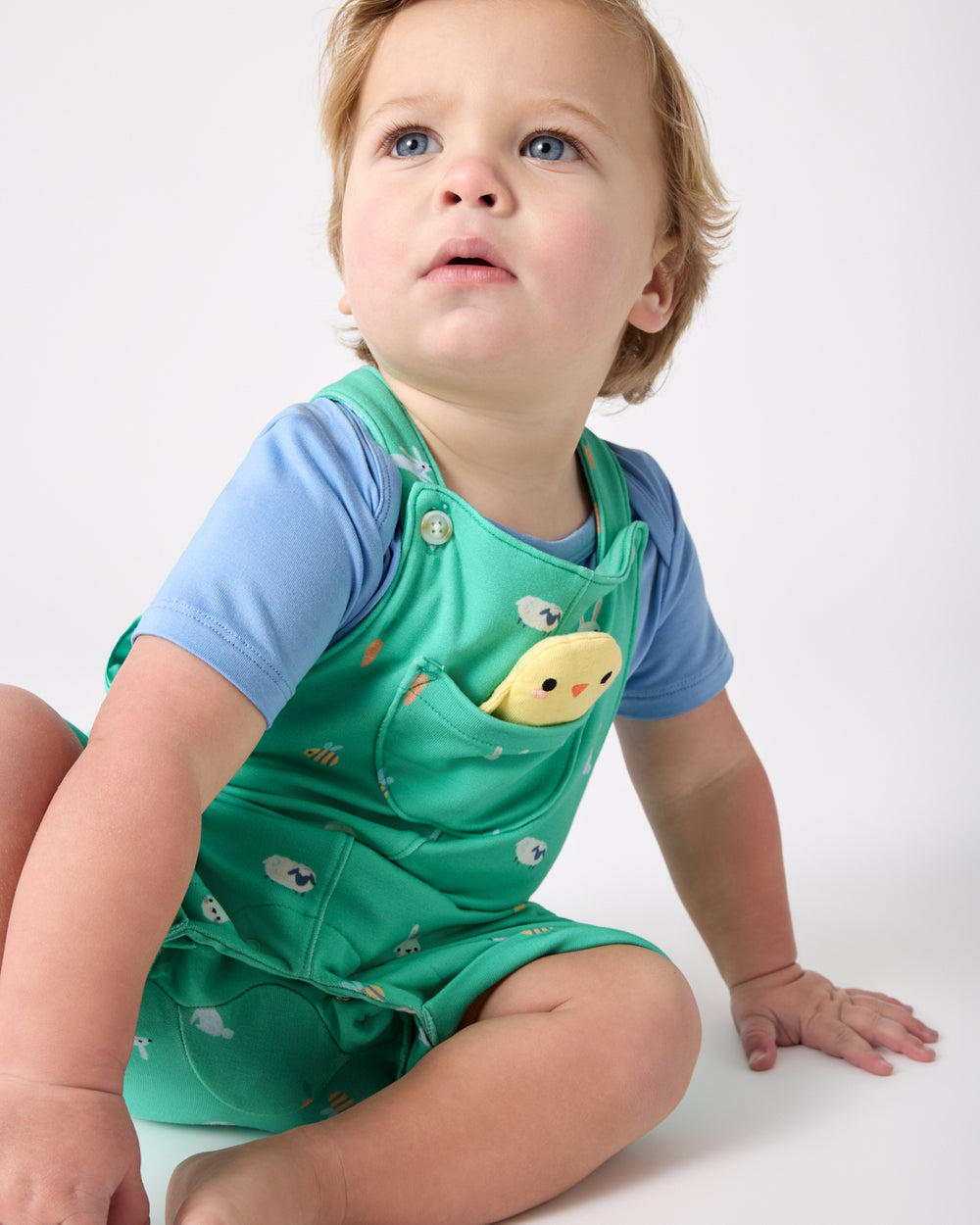 Sitting toddler wearing the Bunny Burrow Shorty Overall Set
